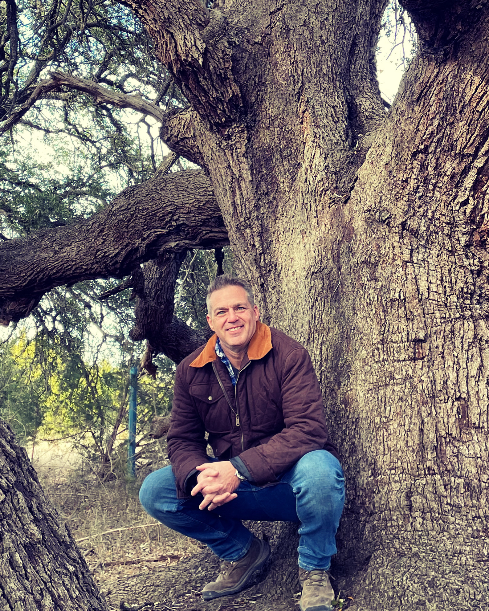 Eric Woytek crouching beside a heritage live oak